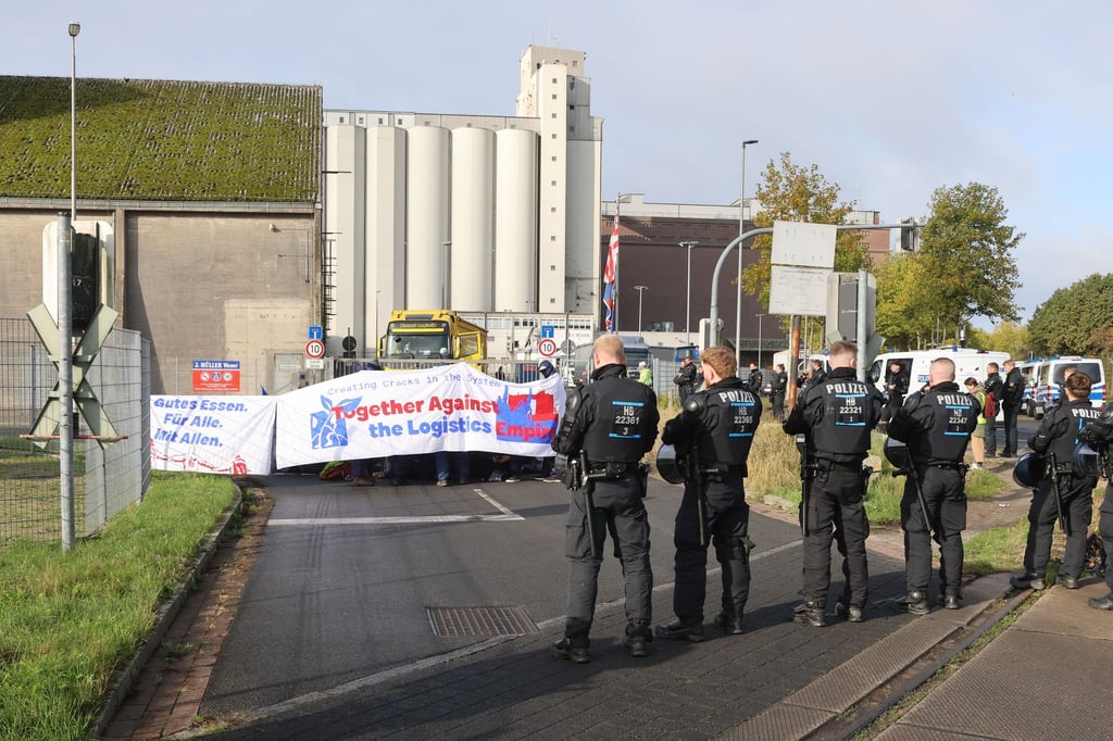 Mit einer Sitzblockade protestieren Aktivisten vor der Zufahrt eines Hafendienstleisters in Bremen-Walle.