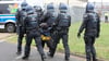 Weil sie ihre Vermummung nicht ablegen wollten, sind einige Protestierende weggetragen worden.