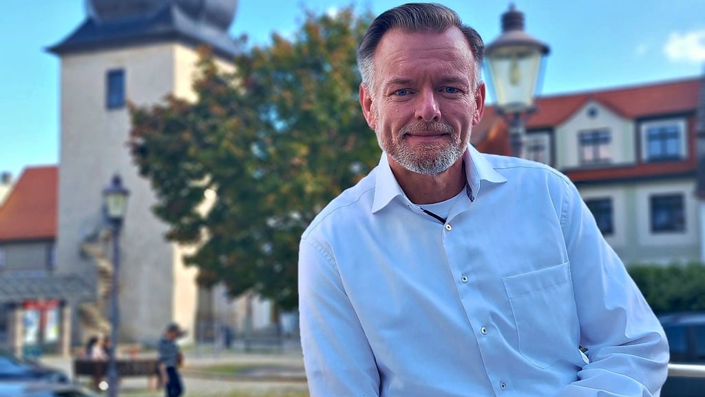André Ulrich tritt als Parteiloser bei der Bürgermeisterwahl in Hettstedt an. Mit einem eigenen Geschäft kämpft er gegen das Ladensterben rund um den Markt, den er mit dem Saigertor im Hintergrund als Fotomotiv gewählt hat.
