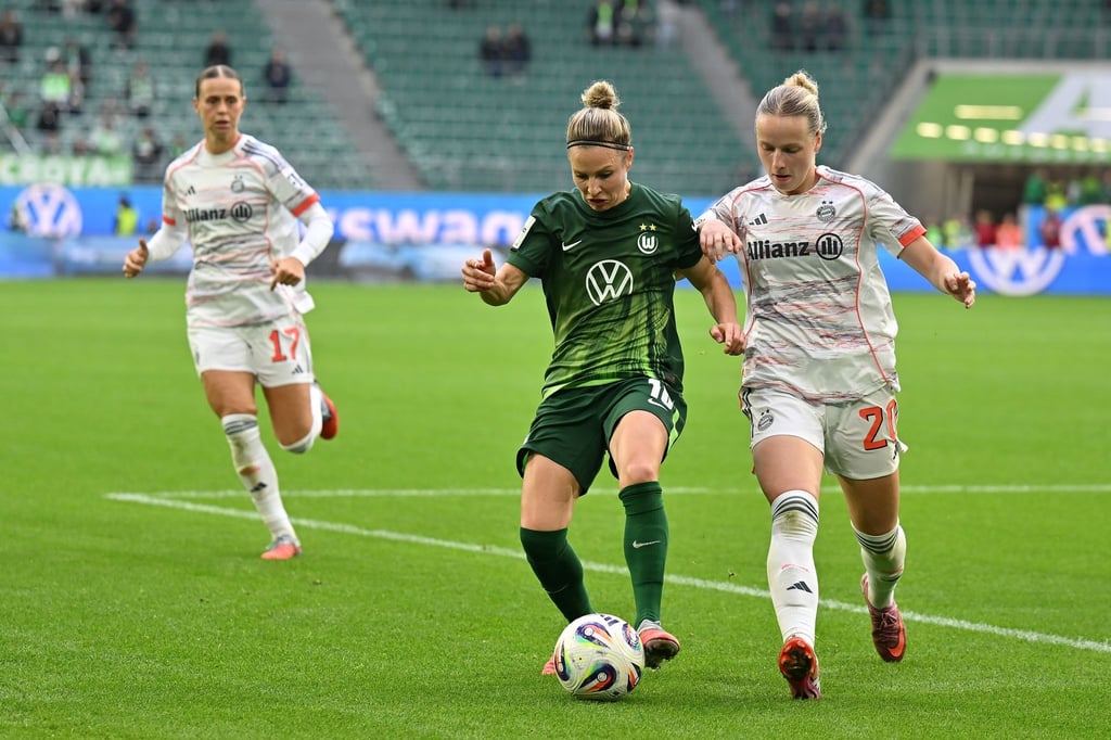 Wolfsburgs Svenja Huth (M) im Zweikampf mit Franziska Kett vom FC Bayern München.