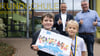 Die zwei Schüler Pepe und Elli der Europagrundschule „Gebrüder Alstein“ in Haldensleben halten den Kalender hoch. Gleich zweimal sind sie mit einem Foto vertreten. Schulleiter Michael Blaschke und Bürgermeister Bernhard Hieber (SPD) freuen sich über das tolle Ergebnis.