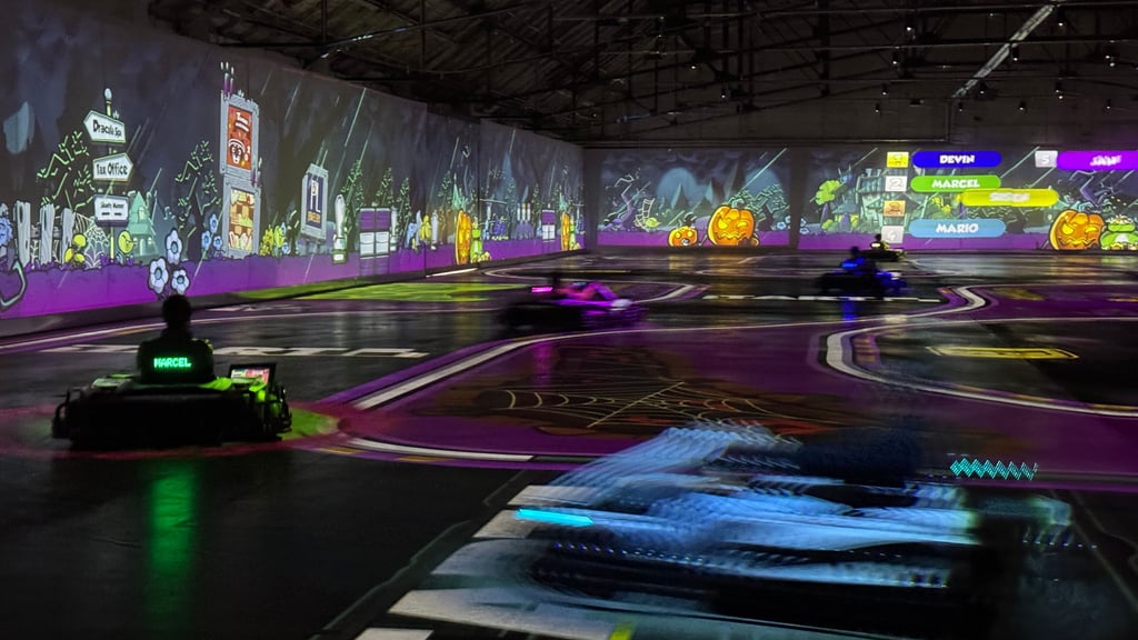 Beim Spiel BattleRace wird die Halle zur echten Mario-Kart-Arena: Die Fahrer jagen über die projizierte Strecke, feuern Raketen ab und weichen virtuellen Ölfässern aus.