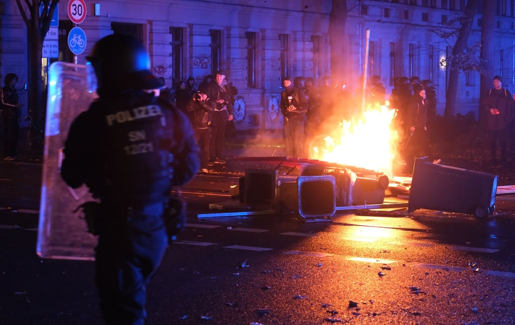 Polizisten stehen auf der Eisenbahnstraße in Leipzig vor brennenden Gegenständen.
