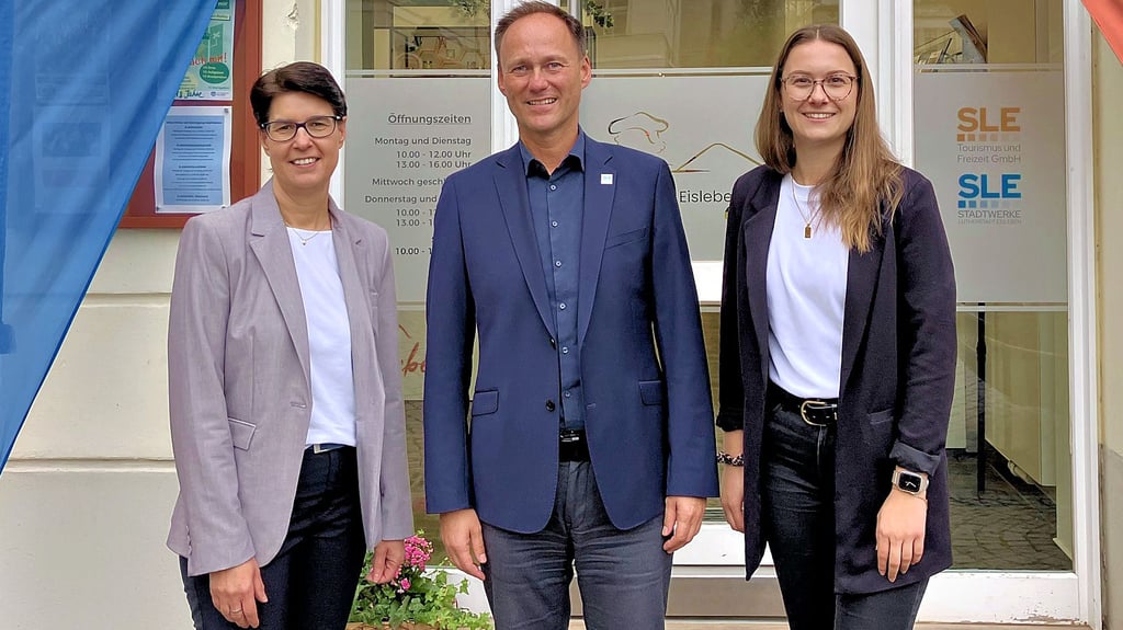 Carola Schmidt (Harzer Tourismusverband), Ronny Strebe (Stadtwerke Lutherstadt Eisleben) und Louisa Mahrenholz, Leiterin der Tourist-Information Eisleben (von links), vor der Geschäftsstelle am Markt in Eisleben.