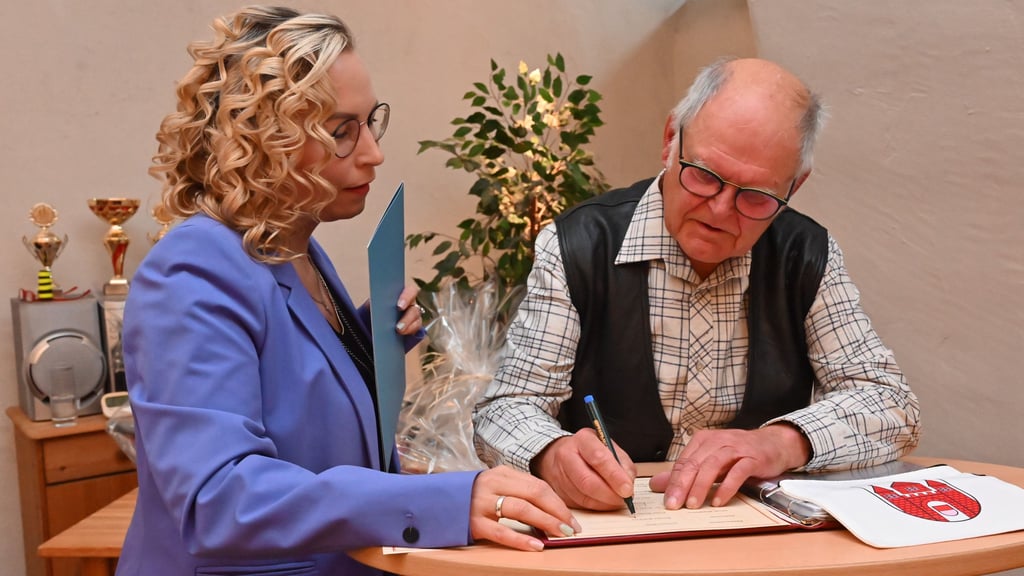 Ernst-Rainer Müller trögt sich im Beisein von Bürgermeisterin Grit Matz (CDU) in das Ehrenbuch der Stadt Wanzleben-Börde ein.