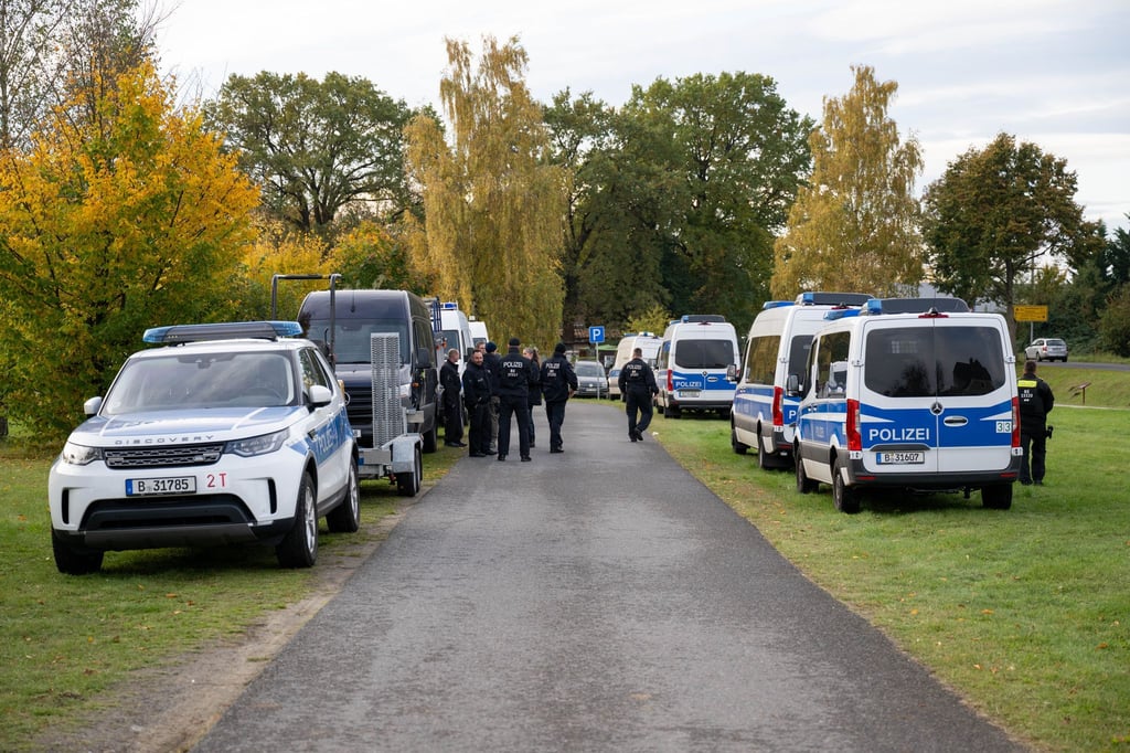 Polizeiautos stehen auf einer Wiese in Tauche.