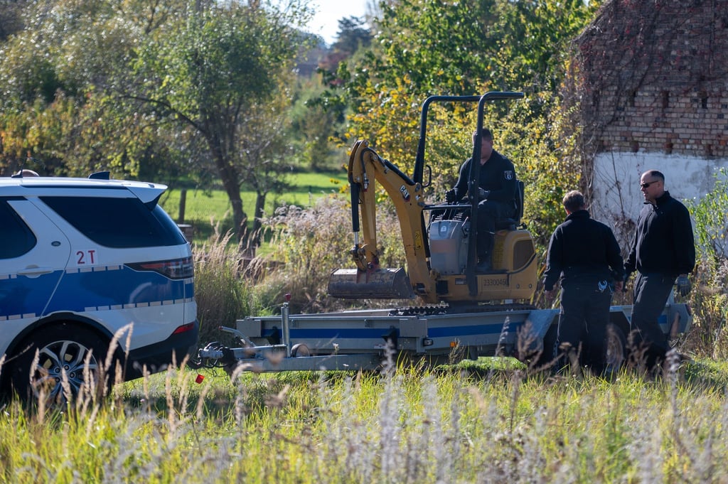 Polizisten untersuchen mit einem Bagger ein Grundstück in Herzberg (Landkreis Oder-Spree).