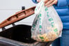 Ein Biomüllbeutel wird in eine Biotonne geworfen. Solche Beutel aus Plastik sind zur Entsorgung des Bioabfalls nicht mehr zugelassen. Bei Tonnenkontrollen in Dessau-Roßlau wurde das mit unter die Lupe genommen.