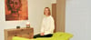 Physiotherapie-Gründerin  Kathleen Flecks sitzt auf einer Behandlungsliege in einem bereits eingerichteten Therapieraum. 