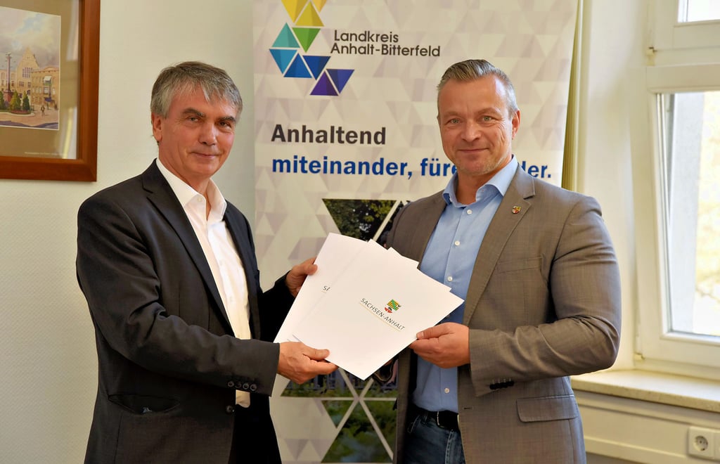 Staatssekretär Steffen Eichner übergibt Landrat Andy Grabner die drei Fördermittelbescheide für den Landkreis Anhalt-Bitterfeld.