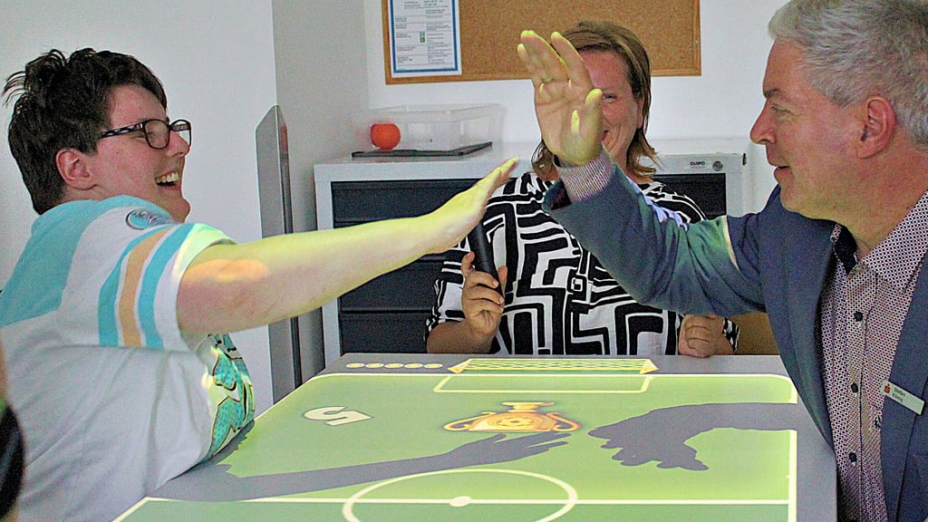 Die Schloß Hoym Stiftung hat nun eine Tovertafel – eine Art digitalen Spieltisch. Bewohnerin Bianca Mecke spielt zur Einweihung gemeinsam mit Sparkassenmitarbeiter Stefan König.