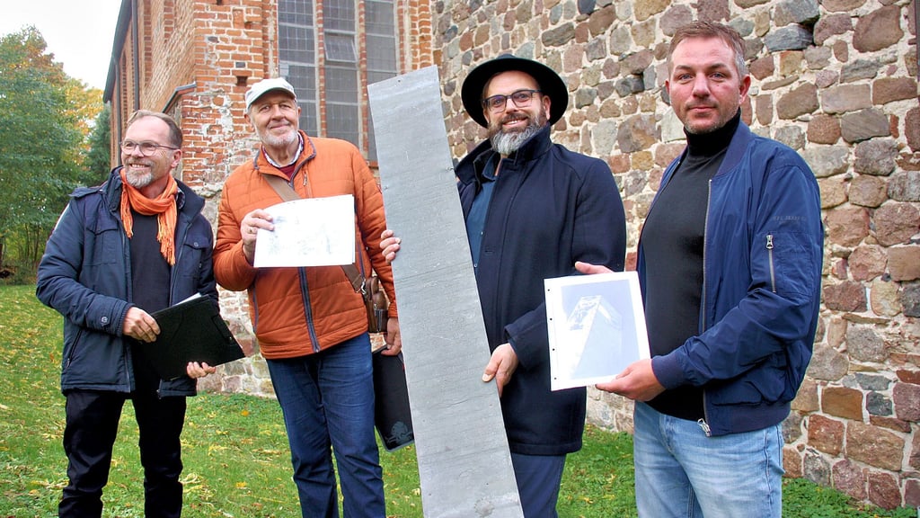 Ralf Engelkamp, Lothar Müller, Florian Fischer und Sascha Sengstock (von links) präsentieren die wiederentdeckte und nun aufbereitete Sargverzierung, eine Blechplatte, vor der Kirche in Krevese.