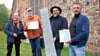 Ralf Engelkamp, Lothar Müller, Florian Fischer und Sascha Sengstock (von links) präsentieren die wiederentdeckte und nun aufbereitete Sargverzierung, eine Blechplatte, vor der Kirche in Krevese.