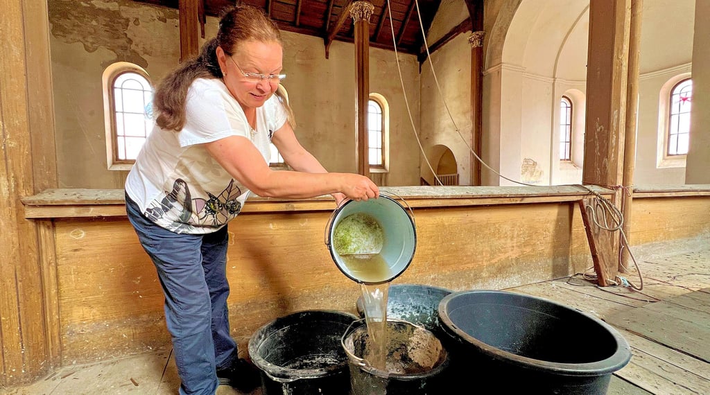 Rita Swillus fängt das Regenwasser, das durch das undichte Dach dringt, mit Eimern auf.