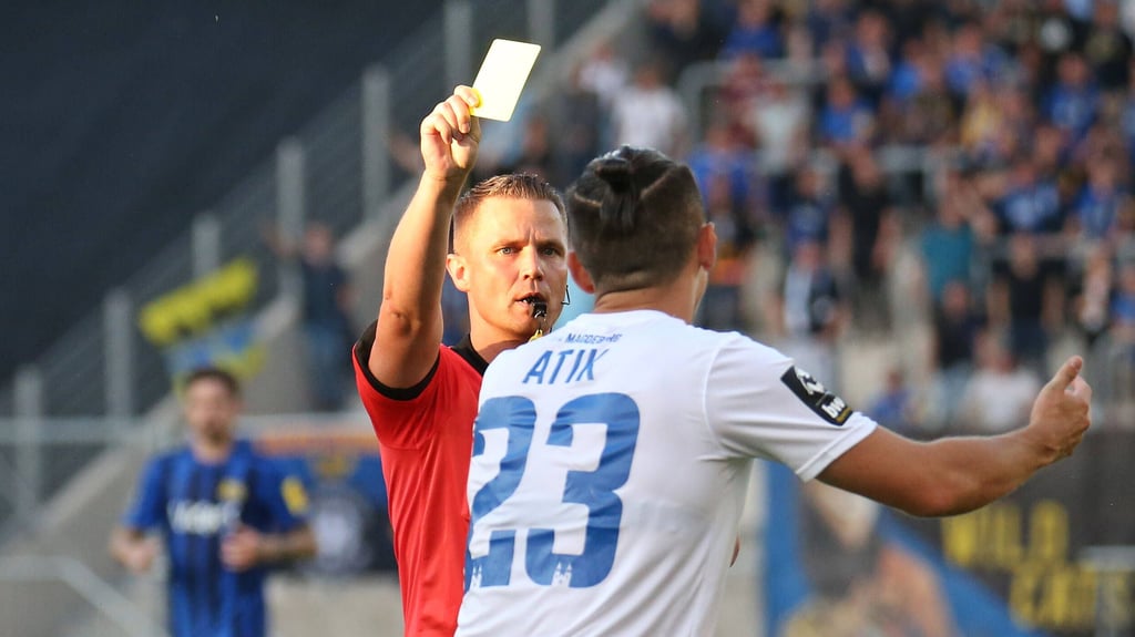 Robert Kampka zeigt Baris Atik die gelbe Karte beim Spiel zwischen dem 1. FC Magdeburg und dem 1. FC Saarbrücken im Jahr 2021.