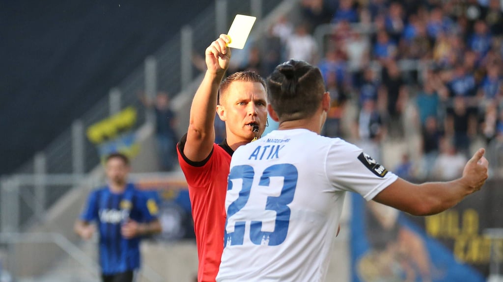 Robert Kampka zeigt Baris Atik die gelbe Karte beim Spiel zwischen dem 1. FC Magdeburg und dem 1. FC Saarbrücken im Jahr 2021.
