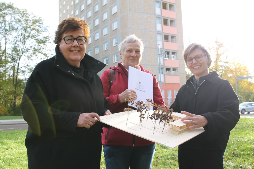 Ministerin Petra Grimm-Benne, Halles Bildungsbeigeordnete Katharina Brederlow und die Architektin Angie Müller-Puch (von links)mit dem Campushaus-Modell: Errichtet werden soll es an Stelle des Hochhauses im Hintergrund in der Richard-Paulick-Straße.