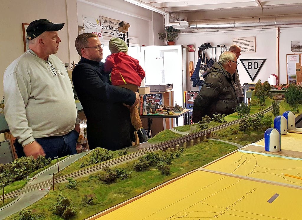 Besucher betrachten im Vereinsraum des Modellbahnclubs die im Aufbau befindliche Anlage mit der Elbebrücke und kommen mit Vereinsmitglied Uwe Müller (l.) ins Gespräch.