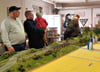 Besucher betrachten im Vereinsraum des Modellbahnclubs die im Aufbau befindliche Anlage mit der Elbebrücke und kommen mit Vereinsmitglied Uwe Müller (l.) ins Gespräch.