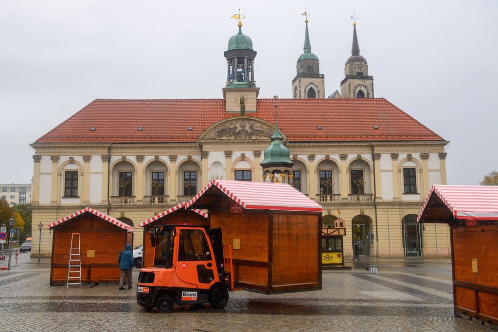 Ein Gabelstapler versetzt auf dem Alten Markt in Magdeburg eine Bude aus Holz.