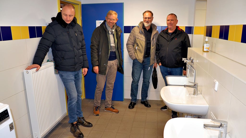 SVA-Präsident Stefan Lipke (r.) führt die Besucher durch die sanitären Anlagen am Altenweddinger Sportplatz. Die Duschen sind erst genau einen Monat alt.