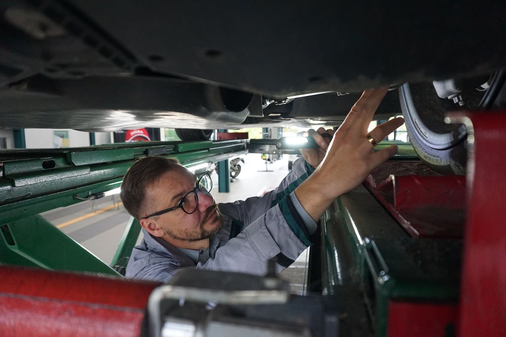 Sebastian König prüft einen Gebrauchtwagen auf einer Hebebühne. Erst beim Blick von unten fallen Mängel auf, die sonst verborgen bleiben.