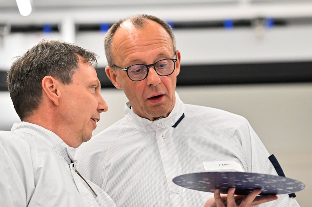 Bundeskanzler Friedrich Merz (CDU) spricht mit einem Mitarbeiter von Globalfoundries im Testlabor im Reinraum  in Dresden.