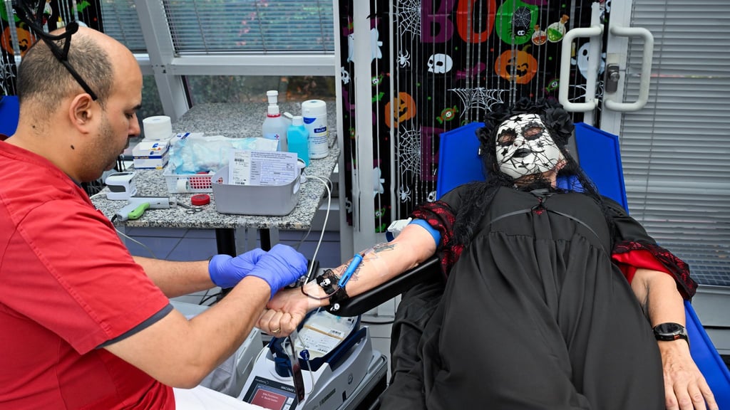 Zwischen Halloween-Deko und im Kostüm spendet eine Frau Blut.