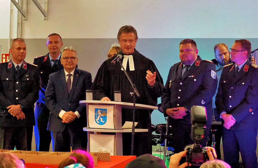 Pfarrer Andreas Börner weiht das neue Gerätehaus in Milzau und mehrere Fahrzeuge.