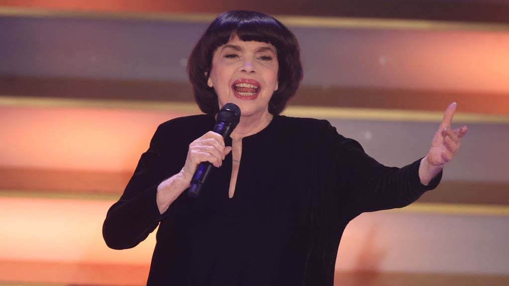 Mit Chanel-Hut und chinesischem Sonnenschirm schützt Chanson-Legende Mireille Mathieu ihre Haut. (Archivbild)