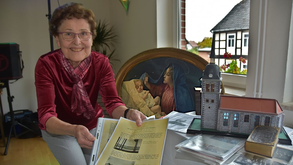 Christa Merker präsentiert das lange verschollen geglaubte Dokument über die Geschichte der evangelischen Kirche in Calvörde. Neben ihr sind auch ein Modell der Kirche und das Gemälde „Maria mit dem Jesuskind“ zu sehen – Erinnerungsstücke mit besonderer Bedeutung für den Heimatverein.