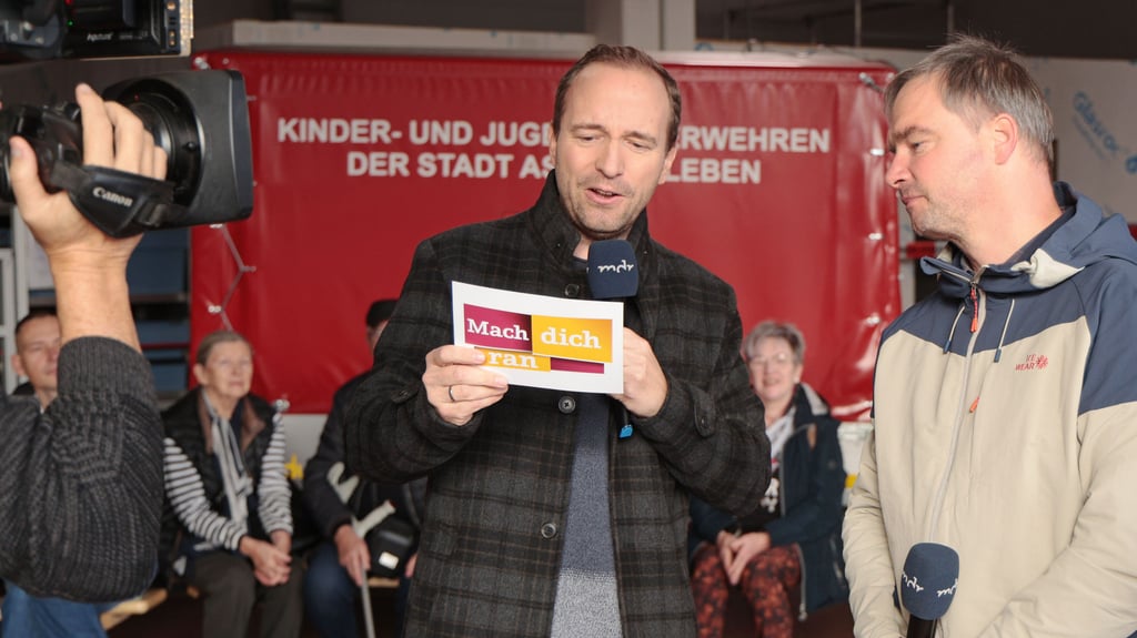 „Mach dich ran“-Moderator Mario Richardt liest OB Steffen Amme die Spielregeln vor.  