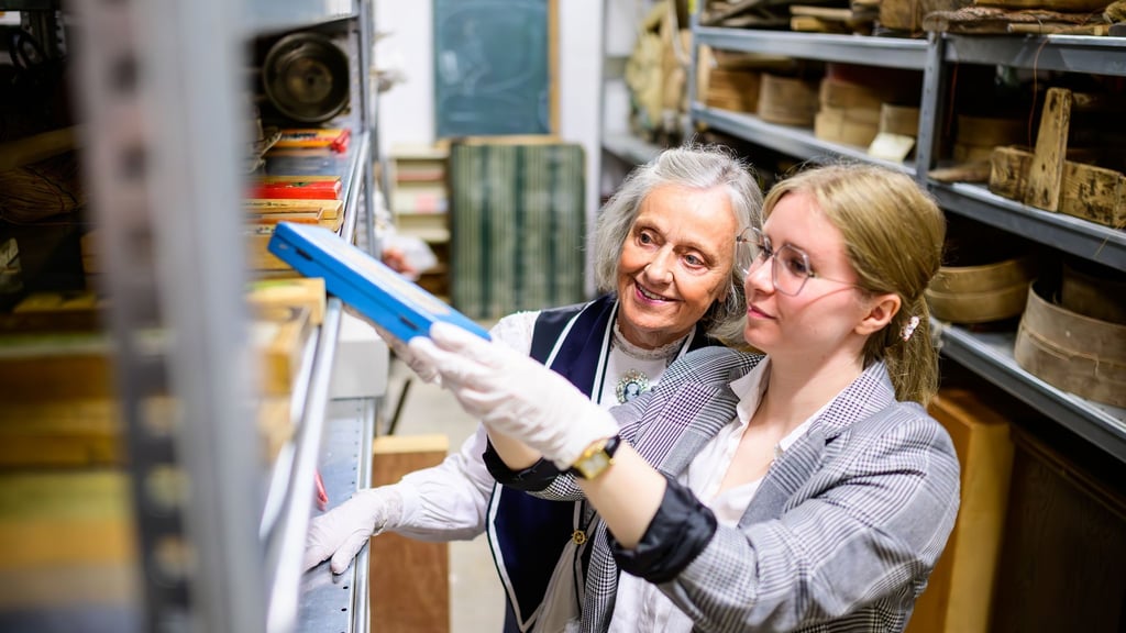 Christine Strüfing (l), ehemalige Lehrerin, und Lea Finzel, Kuratorin, schauen sich im Kiekeberg-Museum verschiedene Exponate an. Christine Strüfing trug tausende Objekte aus der Schule zusammen.