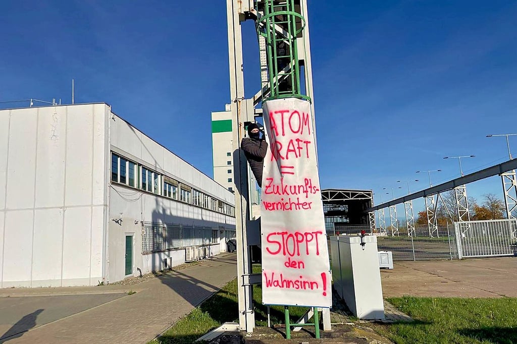 Zwei Aktivisten haben ein Plakat entrollt und sich festgekettet. 