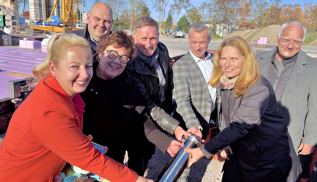 Bürgermeisterin Steffi Syska, Stadtratsvorsitzender Andreas Wolkenhaar, Sozialministerin Petra Grimm-Benne, Bauamtsleiter Jan Martin, Landrat Andy Grabner, Sozialausschussvorsitzende Andrea Goßler und Ortsbürgermeister Mario Willer (v.l.) halten die Zeitkapsel.
