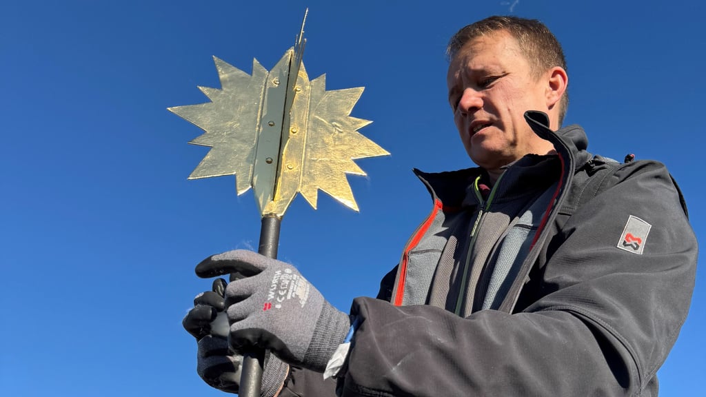 Metalldrücker Thomas Müller montiert den sanierten und neu vergoldeten Stern auf der Spitze des Dingelstedter Kirchturms.