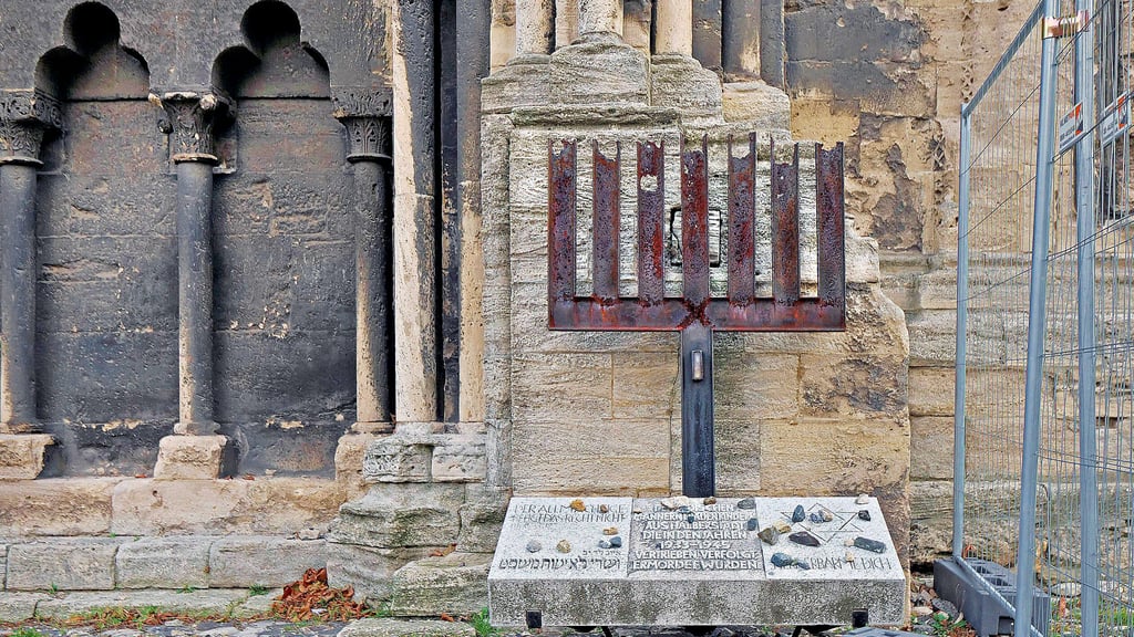 Das erste Holocaust-Mahnmal in der DDR, das auf Betreiben einer Kirchengemeinde entstand: die 1982 von  dem Metallbildhauer Johann-Peter Hinz gestaltete, zerborstene Menora am Portal des Halberstädter Doms.
