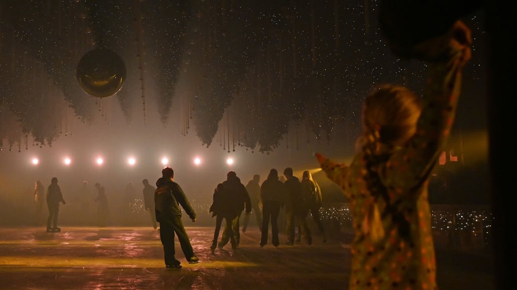 Besucher laufen auf der Eisfläche der Kunst-Lichtinstallation „Dark Matter: Forest Winterlights“.