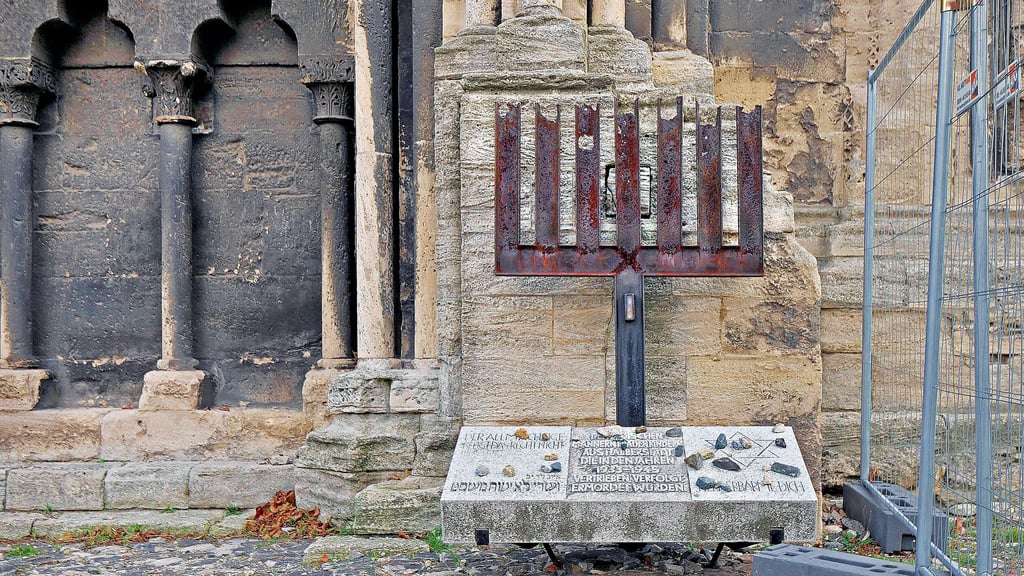 Das erste Holocaust-Mahnmal in der DDR, das auf Betreiben einer Kirchengemeinde entstand: die 1982 von  dem Metallbildhauer Johann-Peter Hinz gestaltete, zerborstene Menora am Portal des Halberstädter Doms.