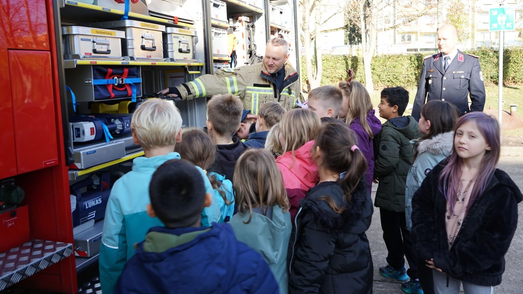 Die Wolmirstedter Feuerwehrleute Christian Brehmeyer und Marcel Tietz erklären Kindern der Gutenberg-Schule, was sich in einem Feuerwehrauto verbirgt.