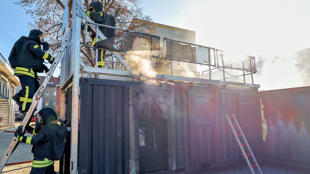 Über eine Leiter steigen die Feuerwehrleute auf und durch eine Luke in den Container. Daraus muss eine Person, dargestellt durch eine Puppe, gerettet werden, bevor der Brand gelöscht werden kann.