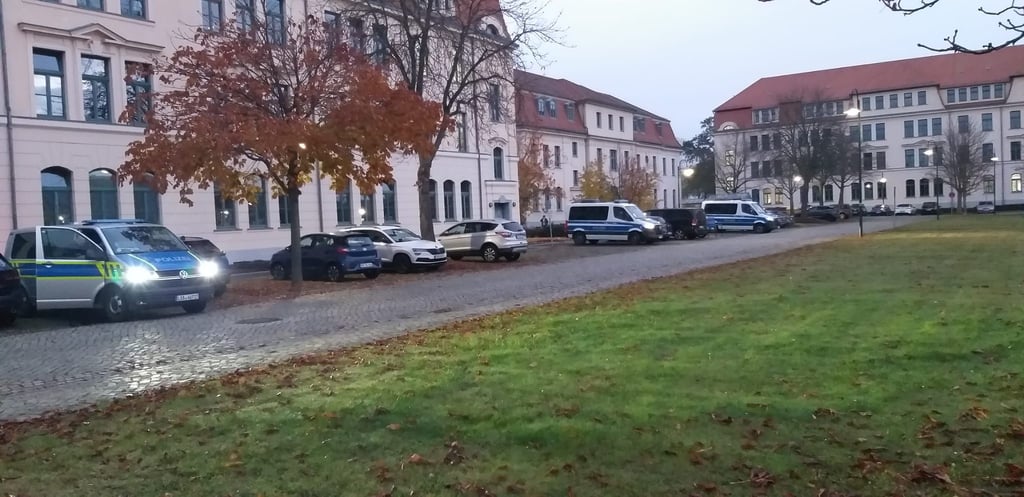 Polizeifahrzeuge stehen in Abständen auf dem Gelände der Ministerien, die an das Behelfsgericht in Magdeburg grenzen.