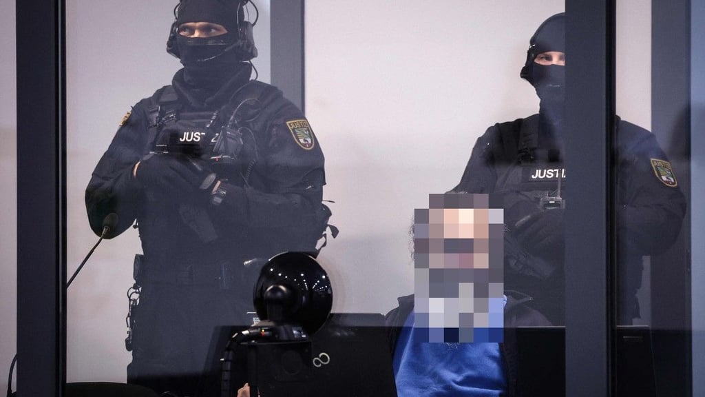 Gefesselt und in einem schusssicheren Kasten verfolgt Taleb A. den Prozess gegen ihn.