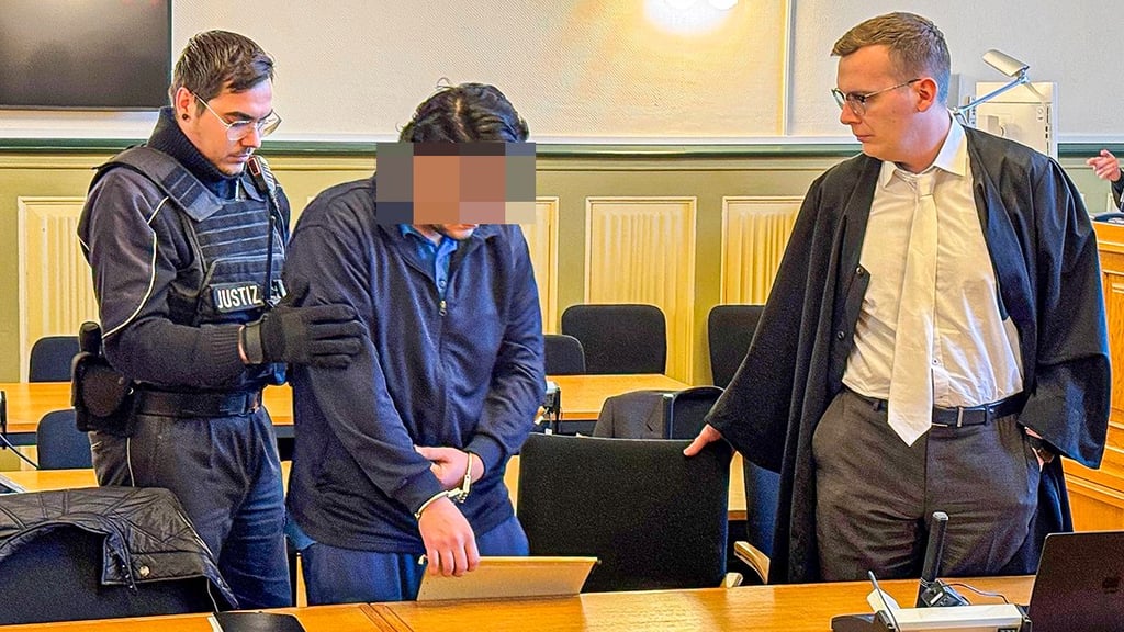 Der 24-jährige Angeklagte wird zum Prozessauftakt am Landgericht Stendal mit Handfesseln in den Saal geführt, rechts sein Verteidiger.