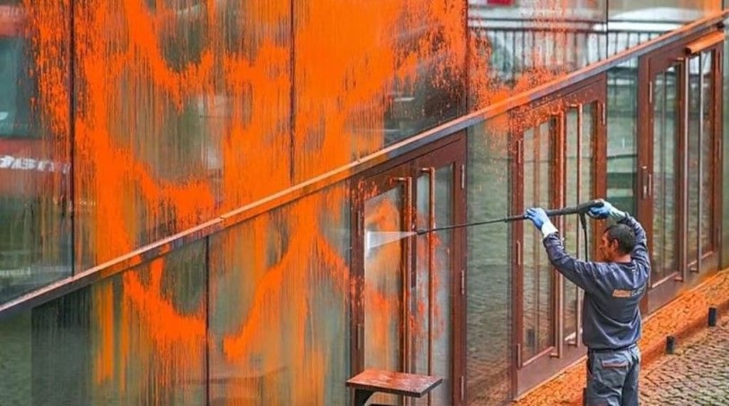 Ein Mitarbeiter einer Reinigungsfirma säubert 2023 die Fassade des Audimax in Halle, nachdem sie von Klimaaktivisten besprüht wurde.