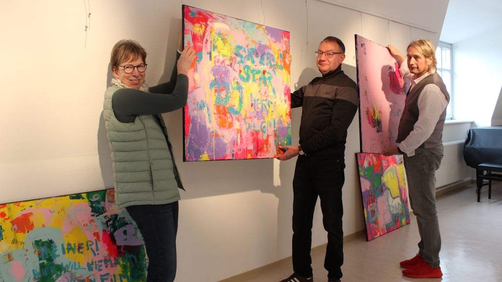 Barbara Hoeft hängt gemeinsam mit Bernd Neumann und Andreas Niemeck (r.) die knalligen Werke in der Kulturfabrik auf. 