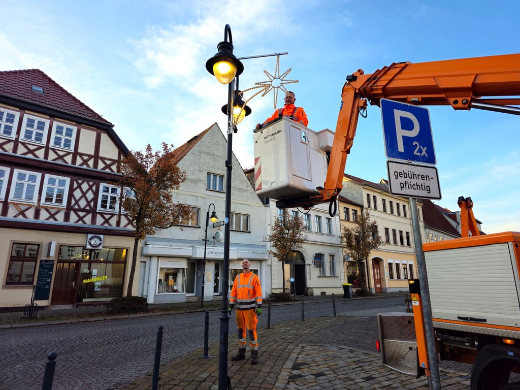 Torsten Trinks (Korb) und Tobias Möhring vom städtischen Bauhof Zerbst installieren in der Stadt die Weihnachtsbeleuchtung, hier auf der Breite.
