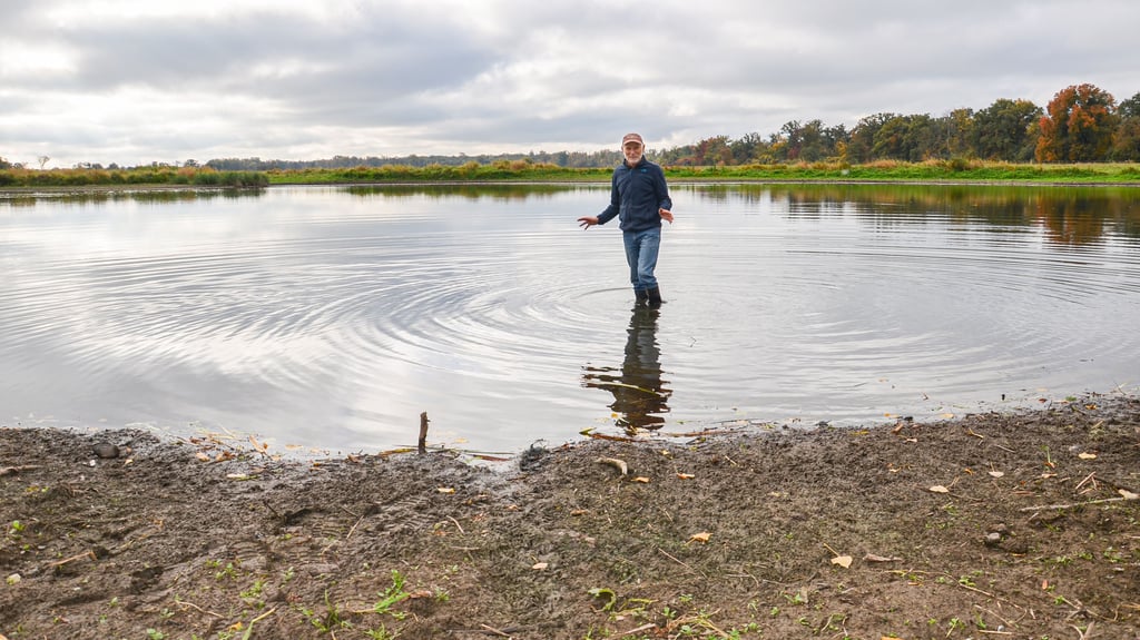Ernst Paul Dörfler steht mit Gummistiefeln im Steckbyer Pfaffensee, der unter Wassermangel und Verschlammung leidet.