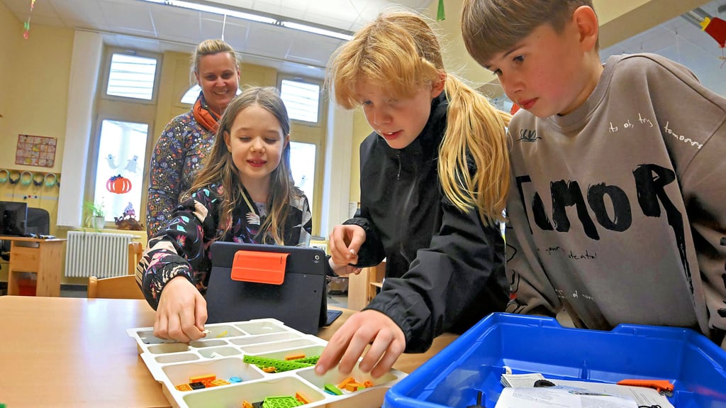 Gemeinsam mit Schulleiterin Claudia Lampert bauen die Viertklässler Lotta, Zoé und Bruno eine Windmühle aus Legosteinen.