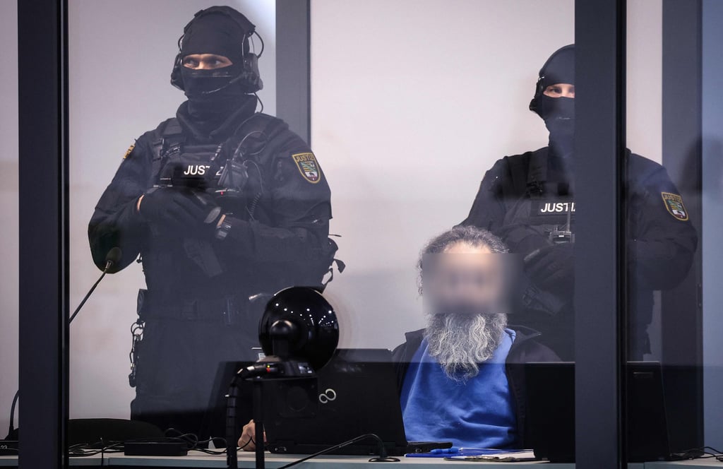 Gefesselt und in einem schusssicheren Kasten verfolgt Taleb A. den Prozess gegen ihn.